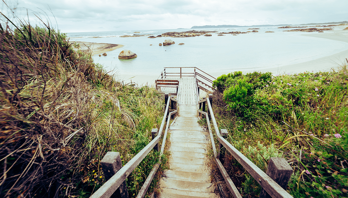wooden steps descending with still calm ocean at the bottom