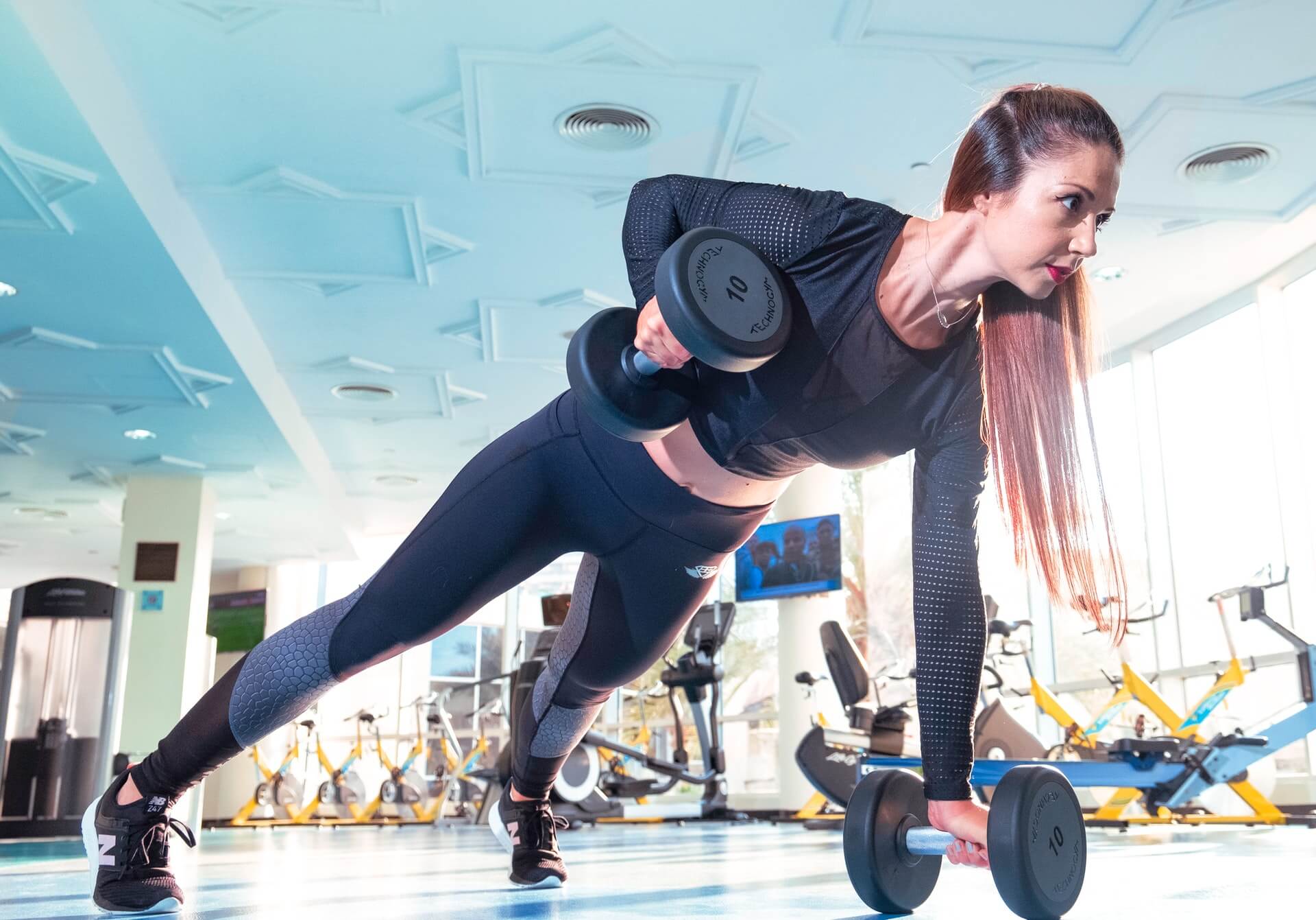 lengthways shot of female lifting dumbbells in plank position